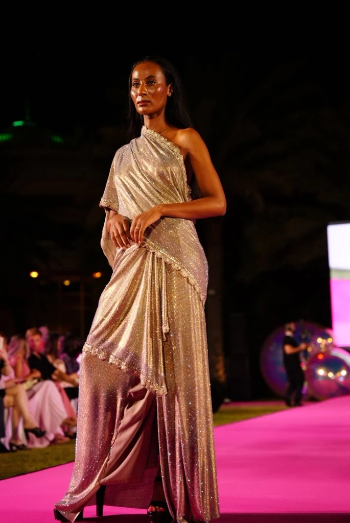 Modelo de vestido champagne brilhante na passarela rosa