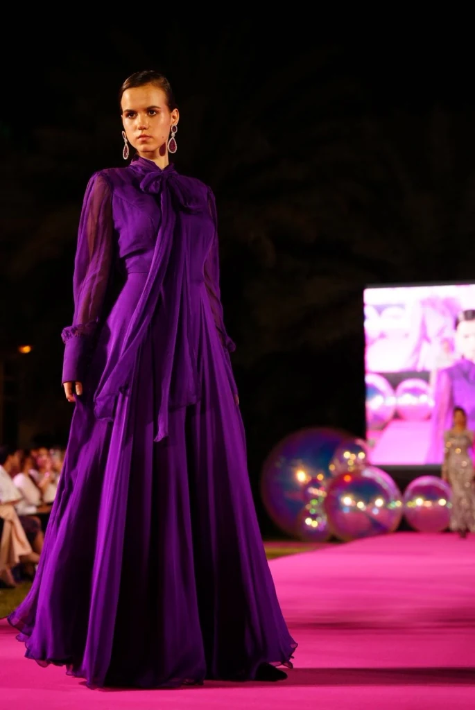 Modelo de vestido roxo longo na passarela rosa